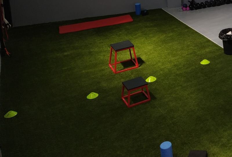 Zona de césped del gimnasio de Global Therapy Mallén, con cajones y conos